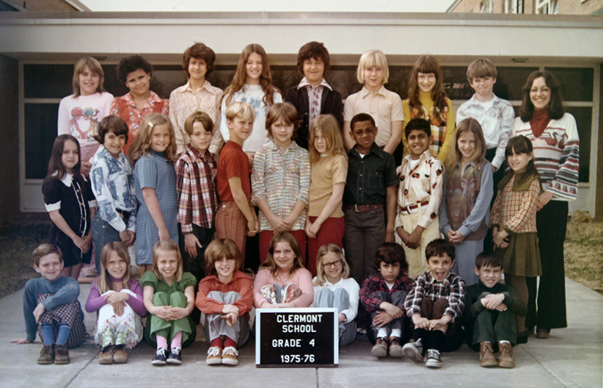 Fourth grade class photograph taken during the 1975 to 1976 school year. 28 children and their teacher are pictured. They are posing on the sidewalk in front of the main entrance to the school.