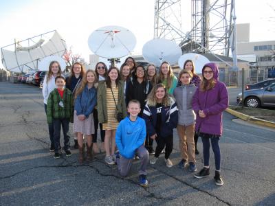 students in group standing among satellite antennas